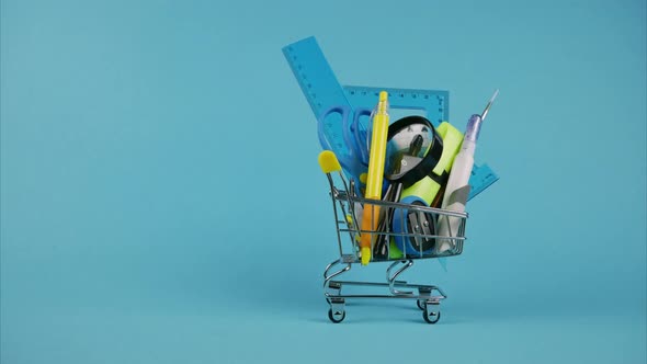 Shopping Cart With School Supplies on Blue Background. Stop Motion Animation 