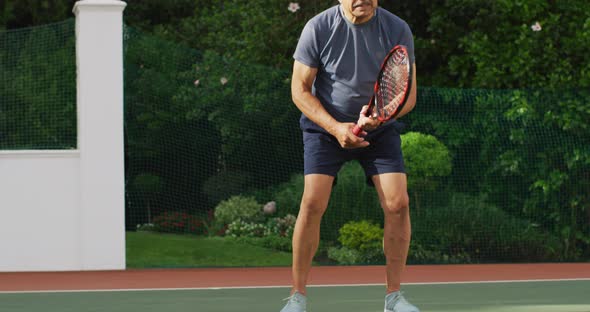Video of focused of biracial senior man playing tennis on tennis court