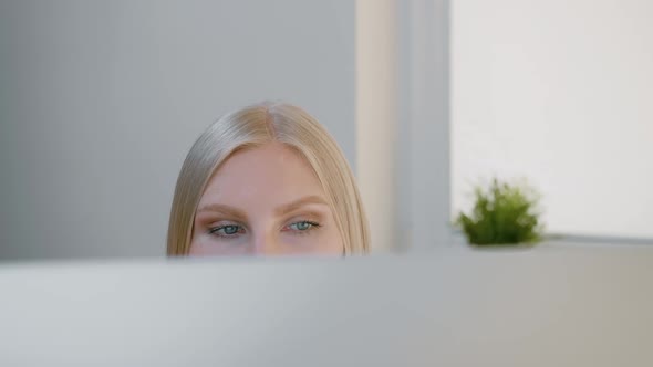 Female Looking at Computer Monitor. Blond Attractive Woman Sitting at Window and Looking Attentively