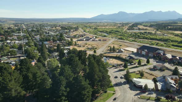 Aerial dolly in of Trevelin main square and houses with mountains in background, Patagonia Argentina
