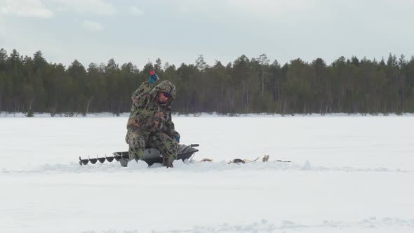 Fisherman Fishing on a Winter Lake Against a Background of Forest Sky