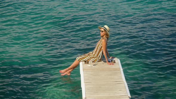 A woman with a glass of white wine on a dock over the Mediterranean Sea in Italy, Europe