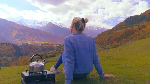 A woman admires the mountains, a kettle is boiling. Georgia.