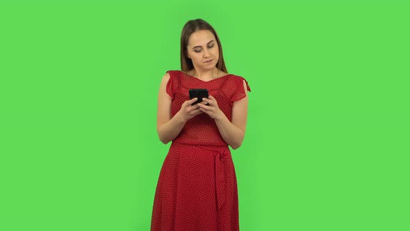 Tender Girl in Red Dress Is Angrily Texting on Her Phone. Green Screen