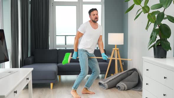 Man Cleaning the House and Having Fun Dancing with a Broom