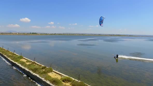 Aerial drone view of a man kiteboarding on a kite board.