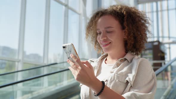 Girl Uses Mobile As Moves Down From Escalator