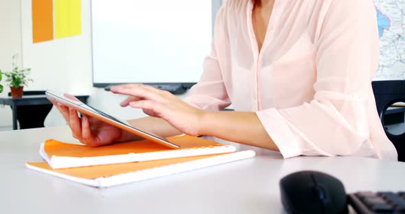 Smiling teacher using digital tablet in classroom