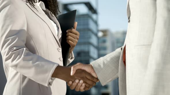 Woman with Folder Shaking Hands with Colleague