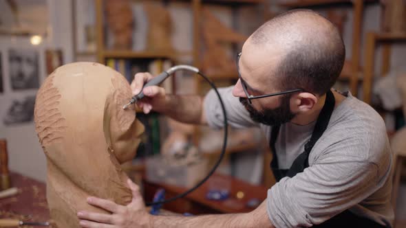 Craftsman carving wooden sculpture in workshop