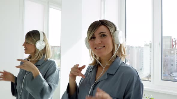 Portrait of cheerful european woman in headphones listening to music