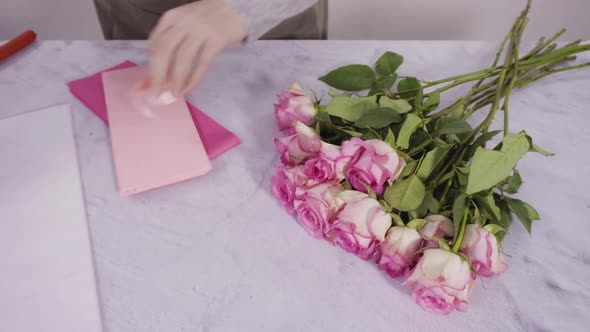 Step by step. Florist arranging a bouquet from pink roses.