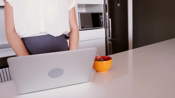 Woman using laptop in kitchen