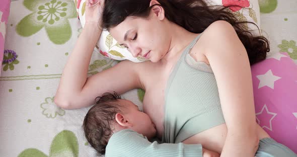 Mother Breastfeeding Her Newborn Baby on Sofa