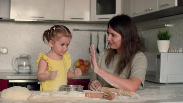 Mom and Child Clap Each Other's Hands While Baking Dough and Laugh