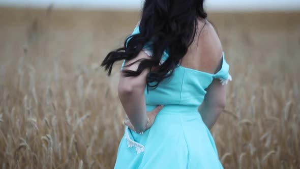 A Beautiful Sweet Brunette Woman in a Field with Hay on a Haystack in a Stylish Dress