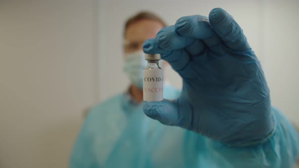 Closeup of Male Doctor Hand in Medical Gloves Holding Coronavirus Vaccine Indoors