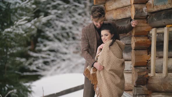 Couple Stands Near a Wooden House