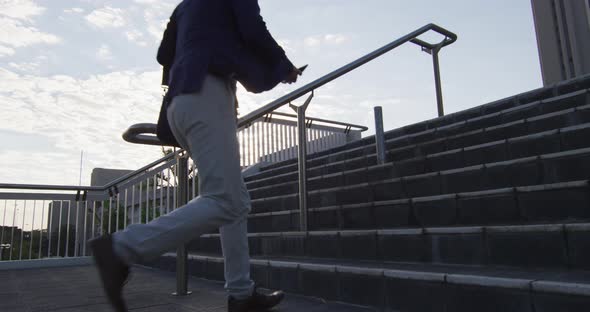 Asian man holding smartphone running while climbing up the stairs at corporate park