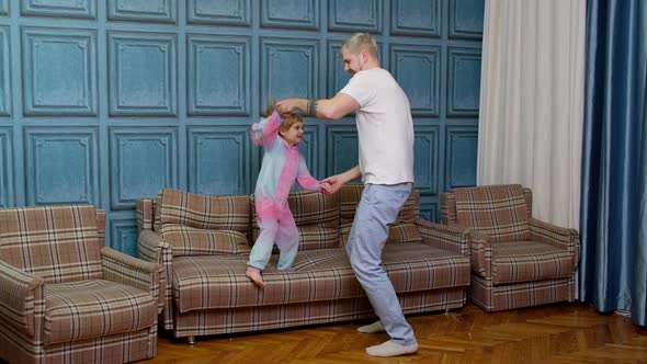 Happy Funny Family Father and Child Kid Daughter Dancing Jumping on Sofa Listening Music at Home