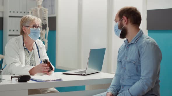 Female Physician Giving Bottle of Pills to Sick Man at Checkup Visit