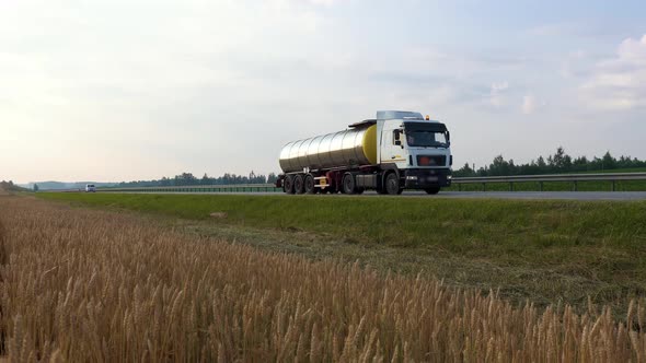 Heavy truck with a tanker truck to carry fuel is driving down a scenic country expressway.