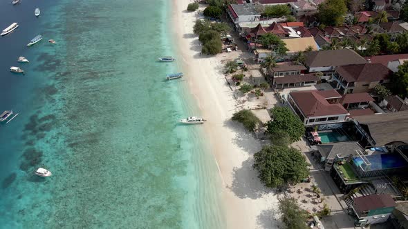 Aerial shot of Gili Trawangan Beach with clear water,parking yachts and luxury hotel resort.