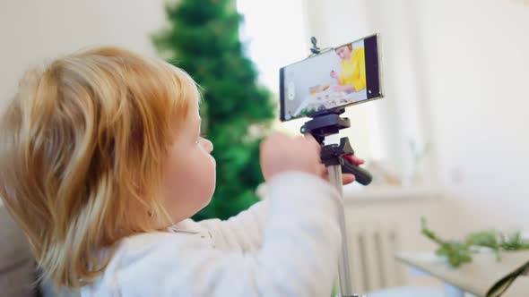 Daughter and her mother record a video stream. A little girl taps on the smartphone screen