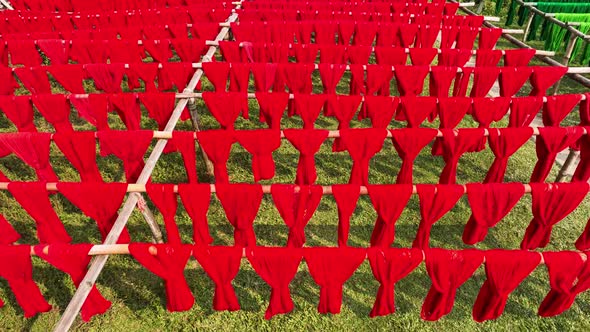 Aerial view of a person hanging to dry red cloths in Dhaka, Bangladesh.