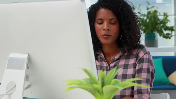 Female executive talking on mobile phone while working on computer at desk 4k