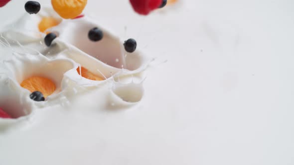 Tossing blueberries, raspberries and mandarine orange in yoghurt. Slow Motion. alt