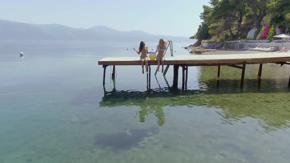 Aerial view of two women sits on wooden deck in Panagopoula, Greece.