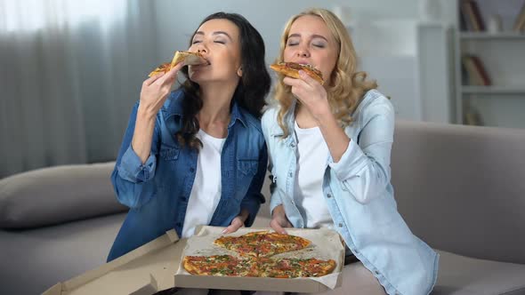 Two Hungry Female Students Enjoying Huge Delicious Pizza Indoors
