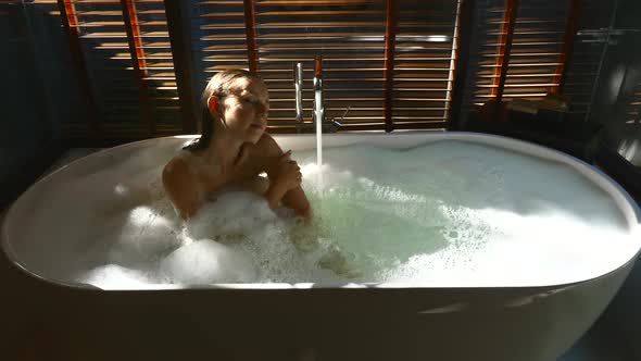 Woman Sitting and Enjoying Bath in Home or Luxury Hotel in Sunny Day