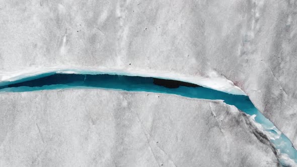 Aerial: top down shot of crevasse in glacier ice sheet, natural formation