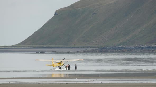 People Unloading From Parked Bush Plane on Water