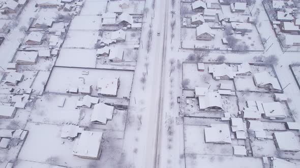 Aerial view of the snow village with private houses and garden plots at winter