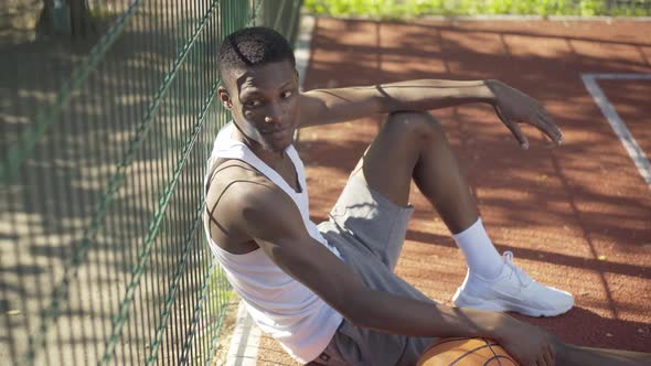 Top View of Happy Young Sportsman Enjoying Sunny Day on Basketball Court. Portrait of Relaxed