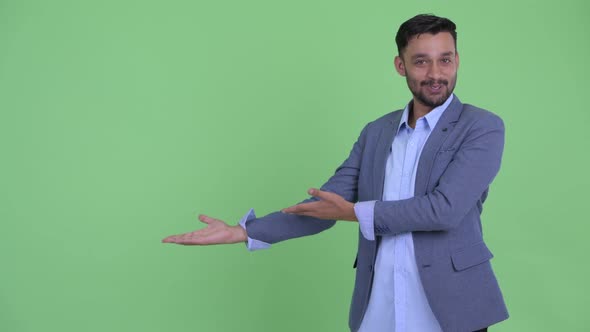 Happy Young Bearded Persian Businessman Presenting Something