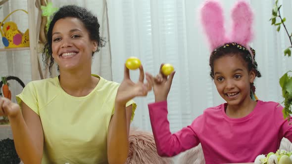 Mom and Daughter with Funny Bunny Ears Laugh and Have Fun with Colored Eggs