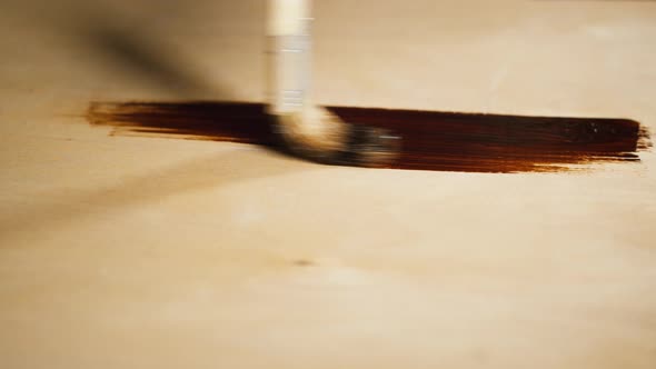 Painting Wood with Brown Paint Using Brush Closeup