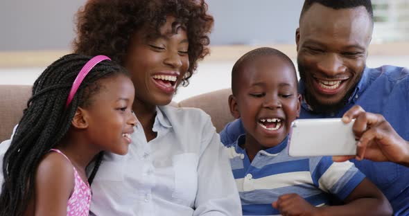 Family sitting on sofa and using mobile phone