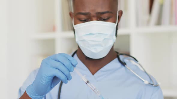 Video of african american male doctor in face mask preparing vaccine