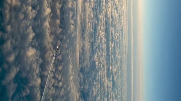 Flying airplane above the clouds, high angle aerial view. VERTICAL format for social media