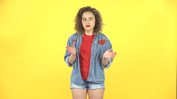 Girl Claps Her Hands Indifferently on Yellow Background at Studio