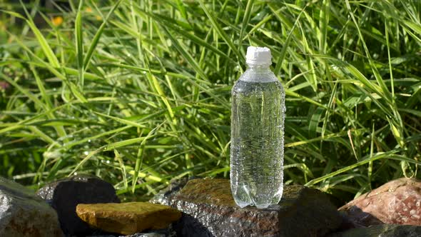 Bottle of water in garden with water drops