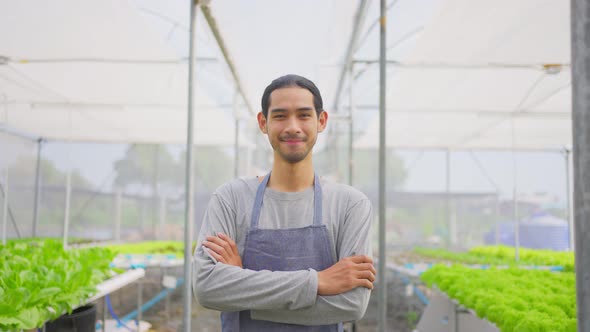 Asian male farmer owner working in vegetables hydroponic farm with happiness and looking at camera.