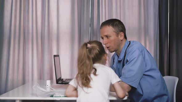 Young Doctor in His Office Talks To Child