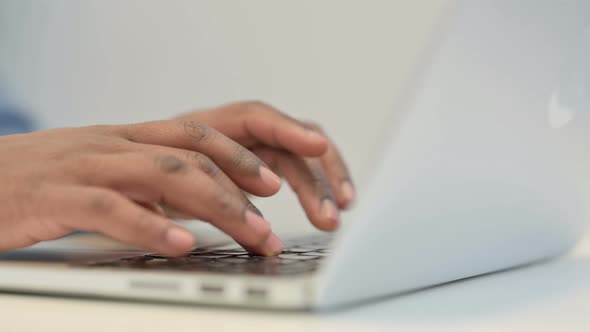 Hands of African Man Typing on Laptop Keypad Close Up