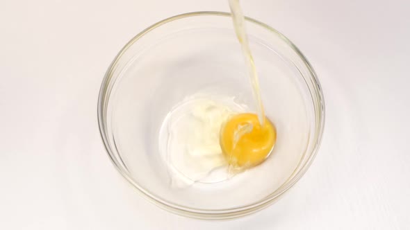 Breaking Eggs for Cooking in Glass Deep Dish, White Background